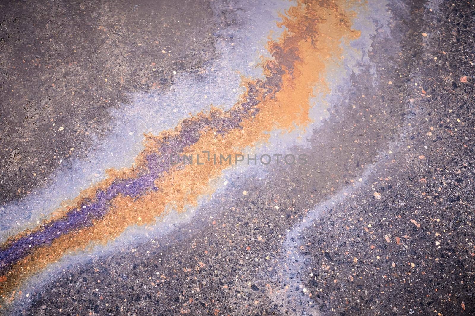 Textured stain of fuel or oil on wet asphalt on a rainy day. The concept of environmental pollution.