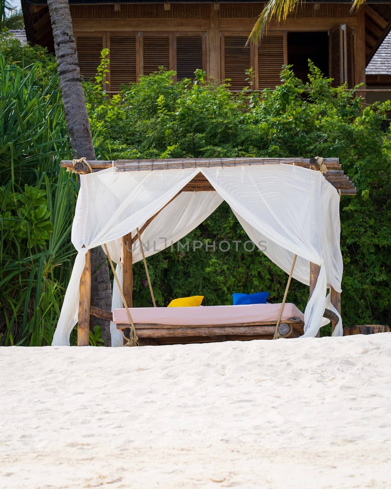 White beach canopy at sunset. Luxury beach tents at luxurious beach resort. Summer beach concept, carefree, rest seaside, Nobody on the beach.Garden on the back.