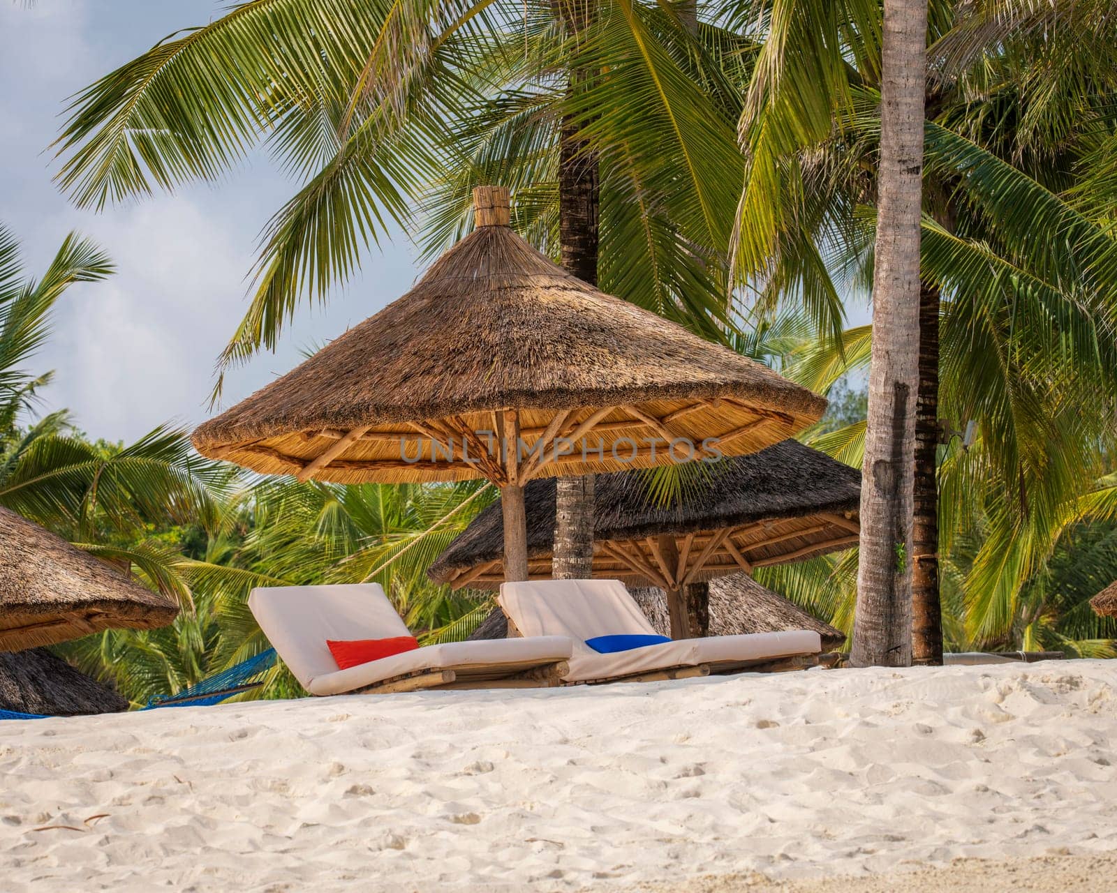 Nice wooden beach umbrella and luxury beach loungers on the beach at sunset by Robertobinetti70