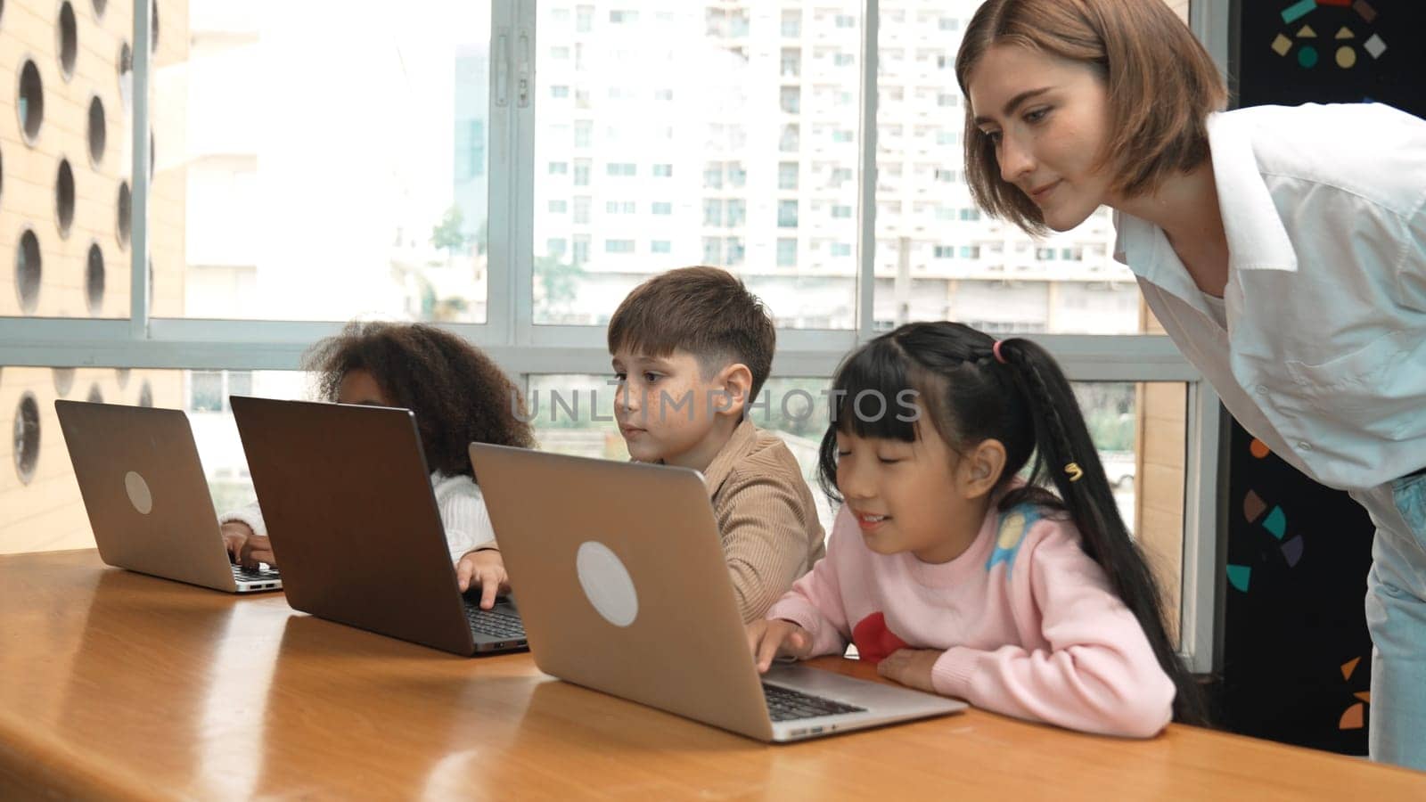 Smart teacher teaching and looking student using laptop at classroom. Professional instructor explained about programing engineering code or prompt while studying and learning program. Erudition.