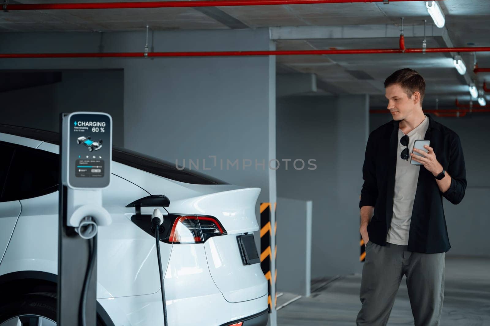 Young man travel with EV electric car to shopping center parking lot charging in downtown city showing urban sustainability lifestyle by green clean rechargeable energy of electric vehicle innards