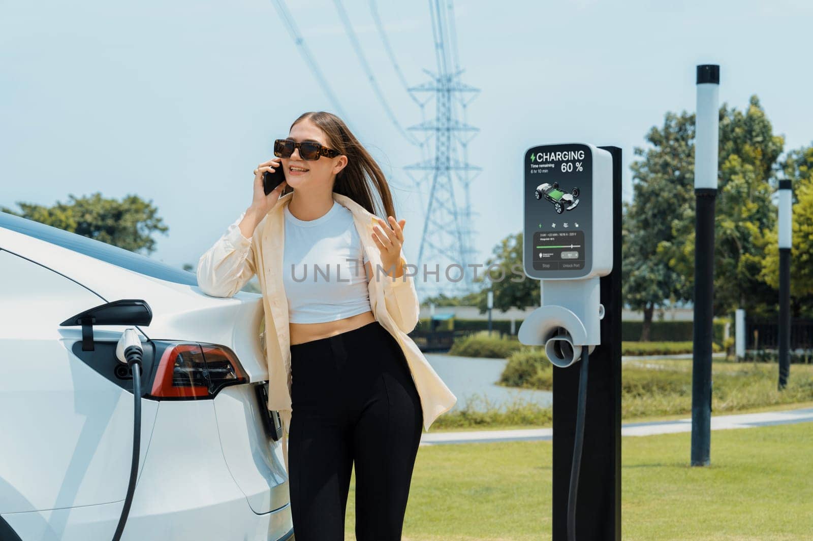 Young woman recharge EV car battery at charging station. Expedient by biancoblue