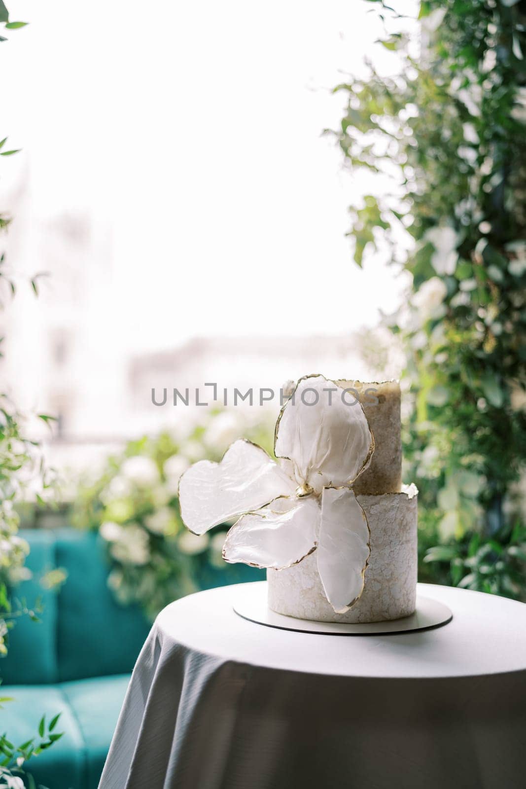 Two-tier wedding cake with a bow stands on a table on the balcony. High quality photo