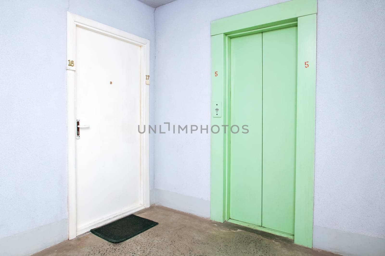 Green old elevator in the hallway and door to the apartment