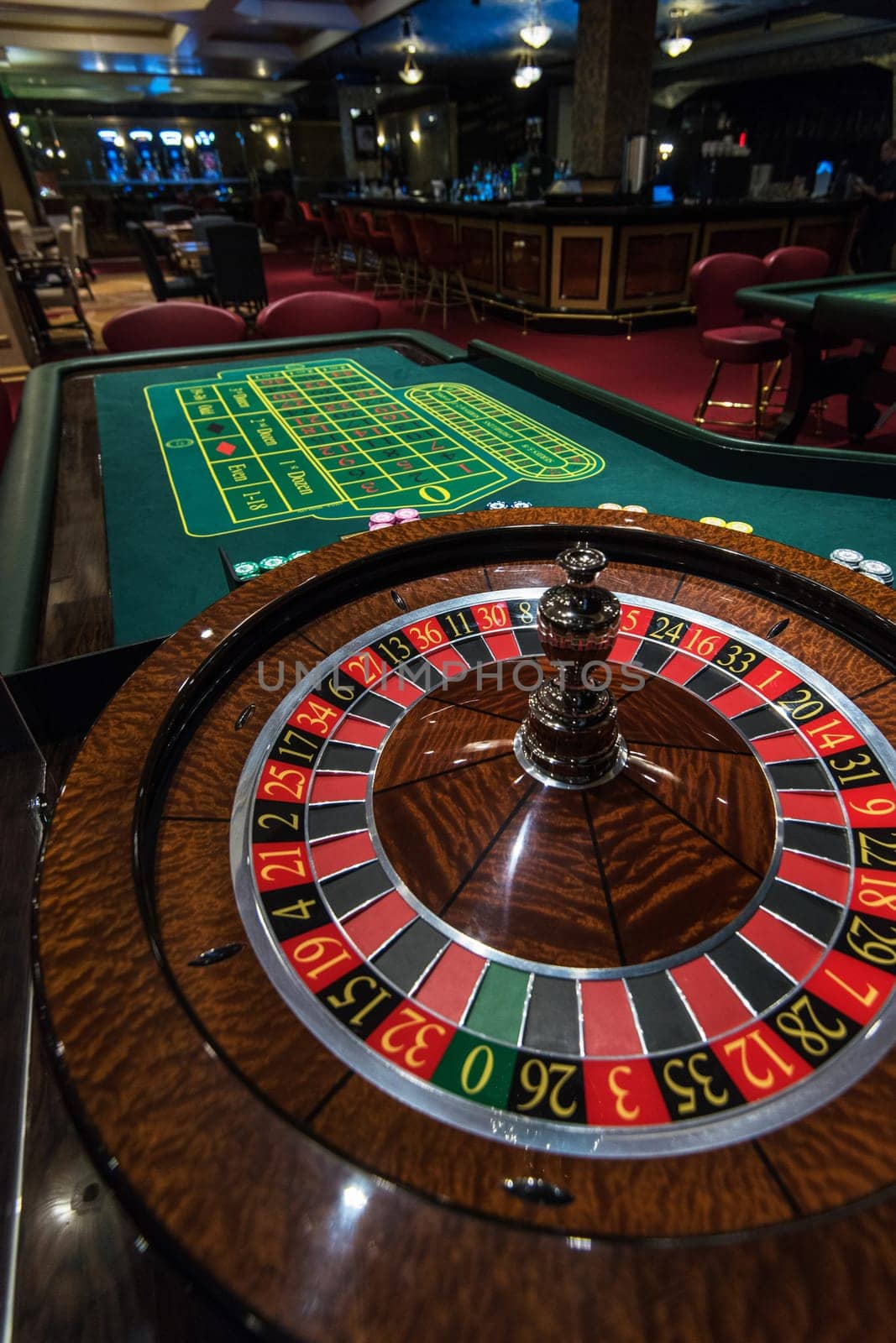 Casino, gambling and entertainment concept - roulette table and stack of poker chips