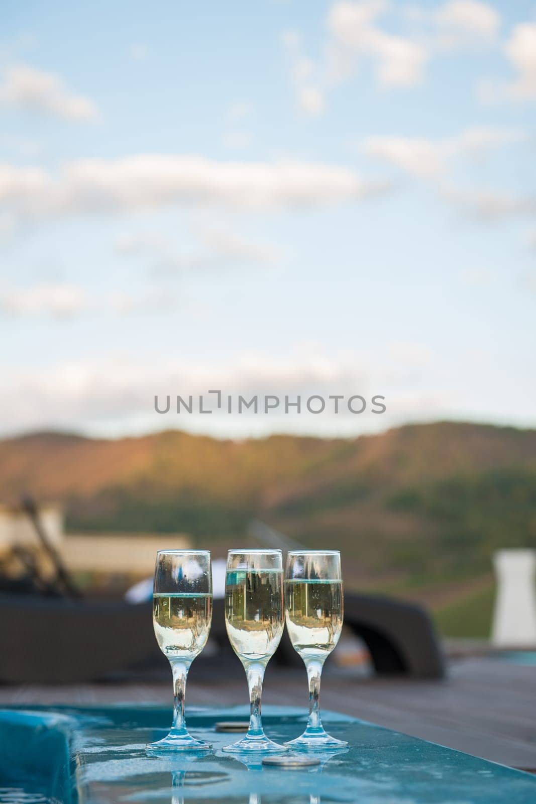 Three glass of cool champagne wine outdoor in a restaurant pool, terrace in mountain