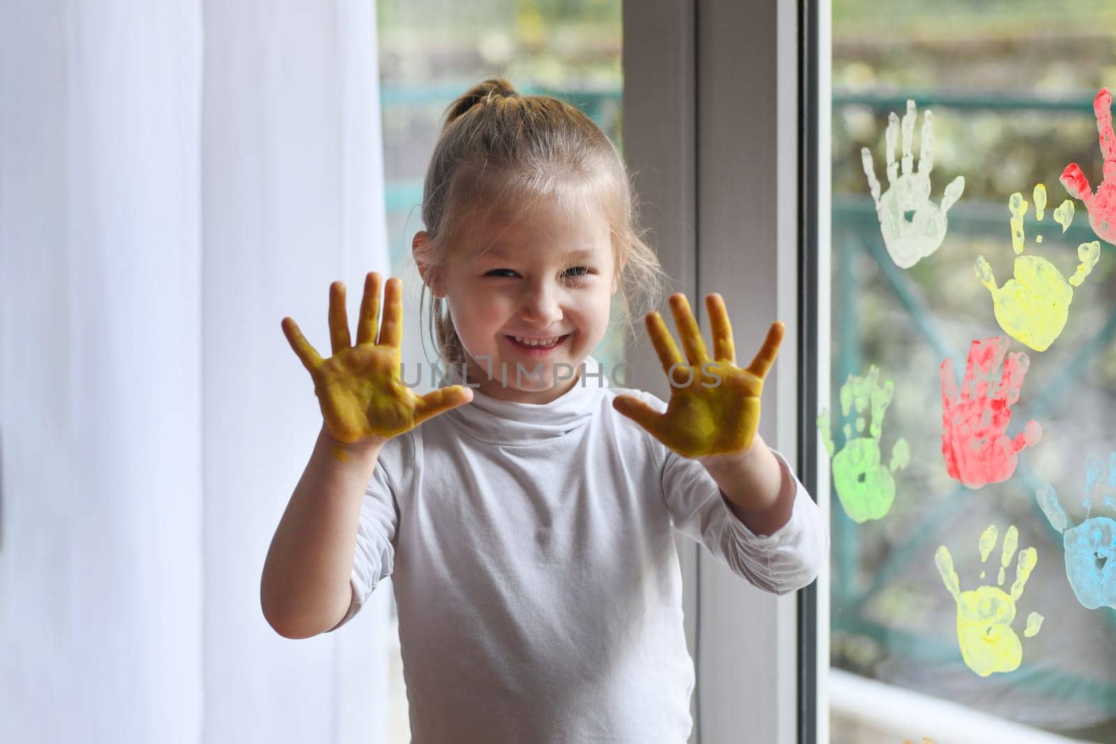 Girl paints with palms on the window. Quarantine Stay at home