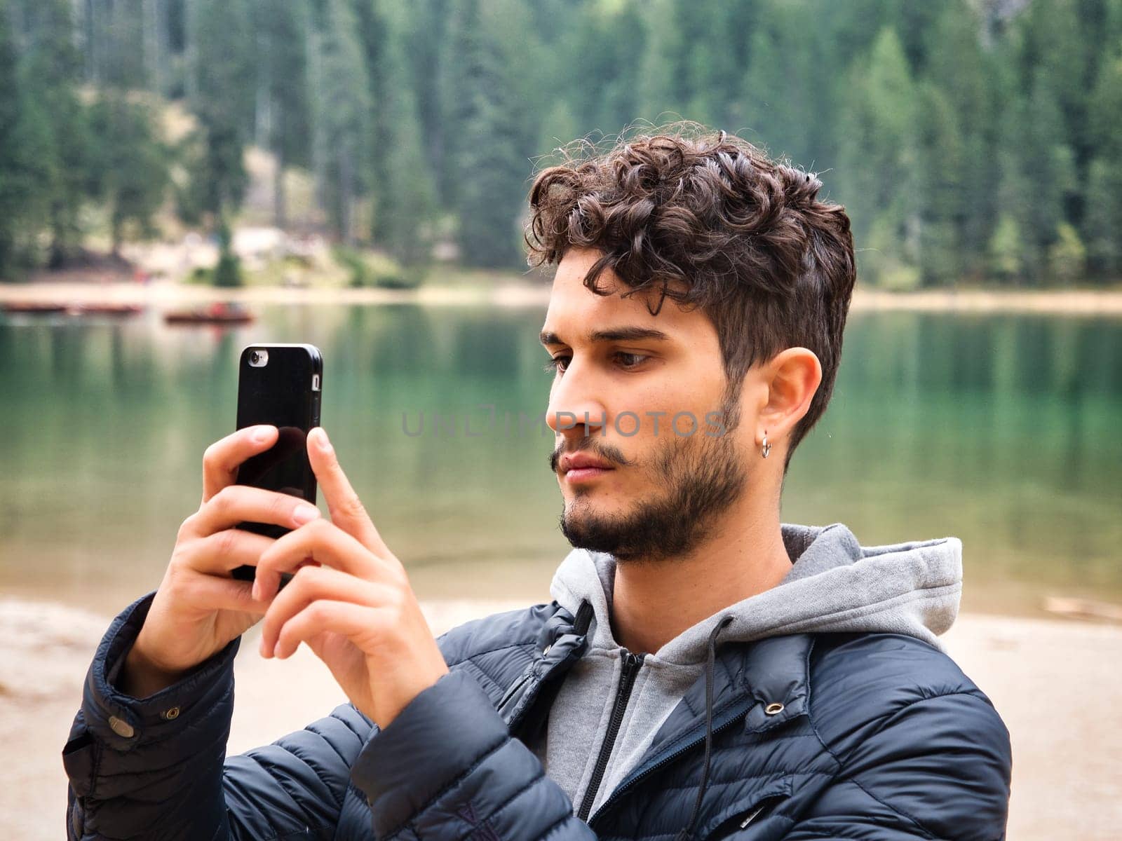 A man standing on a boat holding a camera. Photo of a man capturing the breathtaking beauty of the Dolomites from a boat in Italy