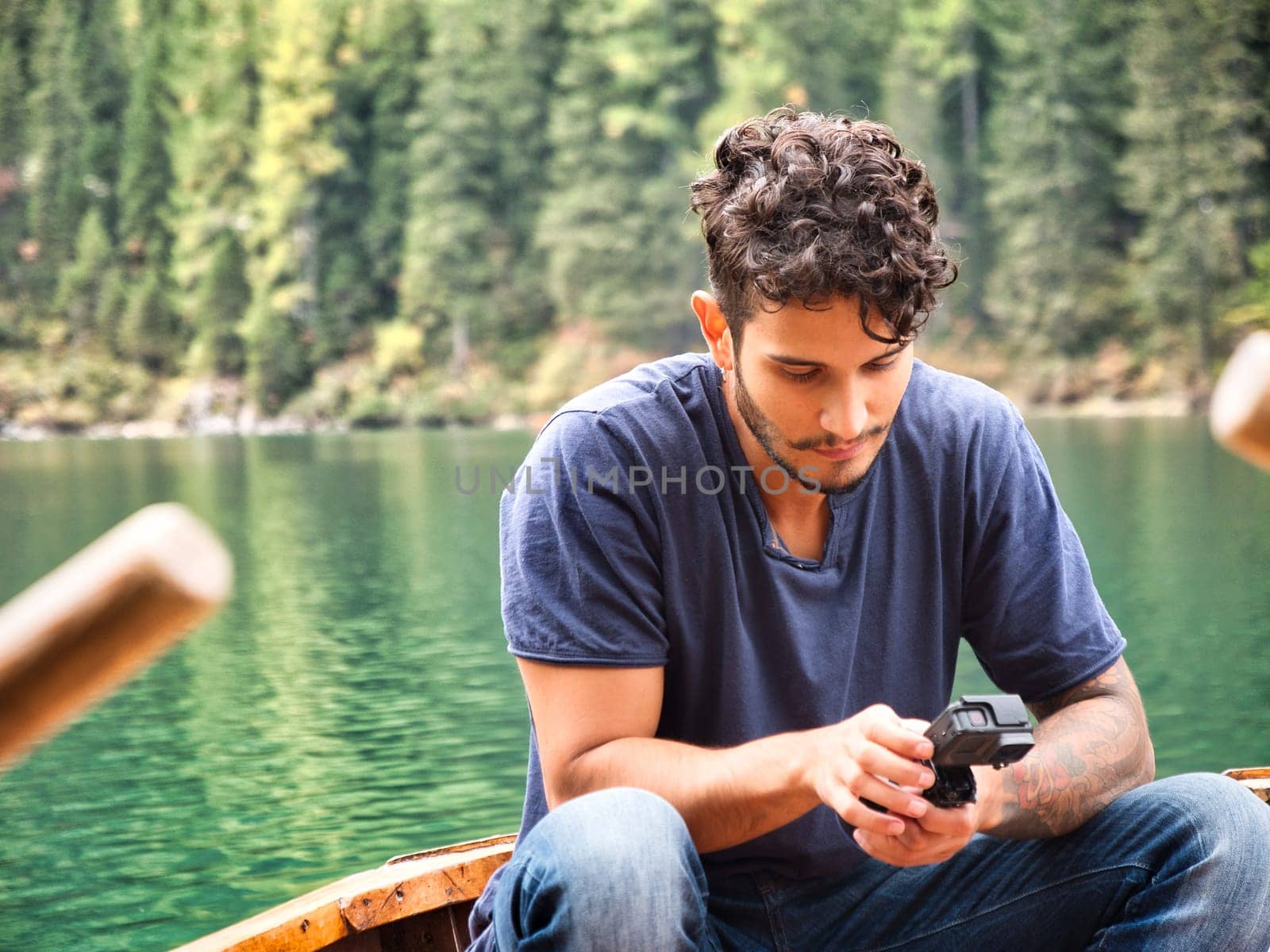 A man standing on a boat holding a camera. Photo of a man capturing the breathtaking beauty of the Dolomites from a boat in Italy