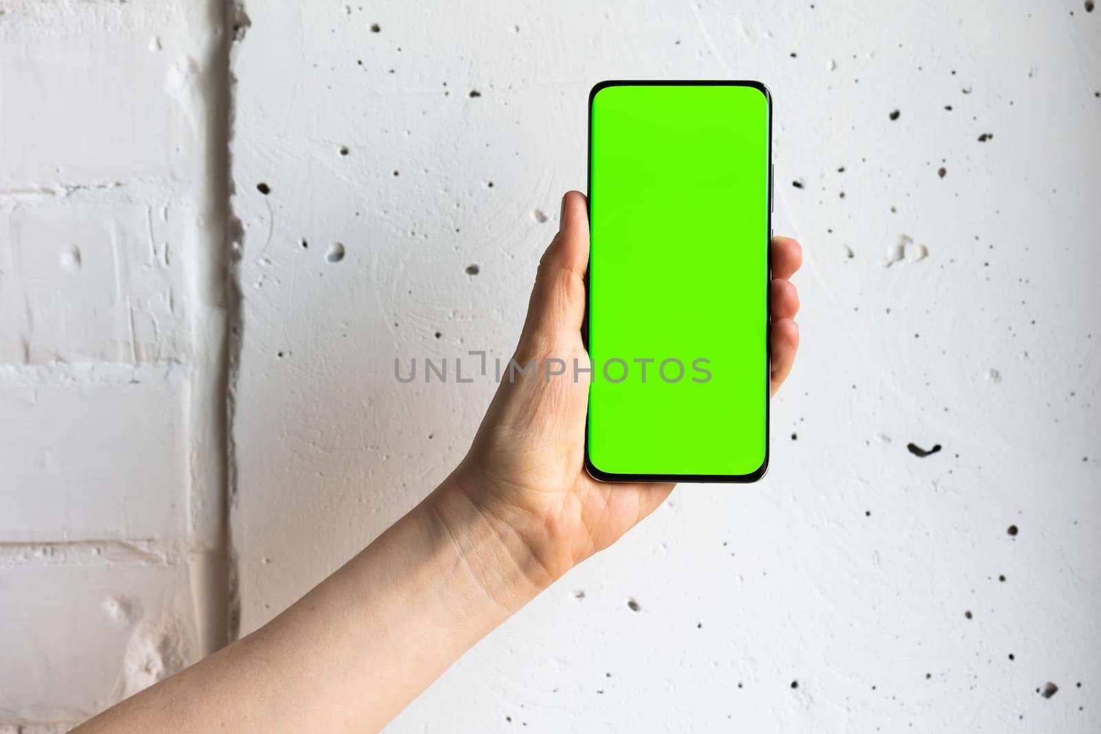 Mockup image of a person holding smart mobile phone with blank green screen. by sarymsakov