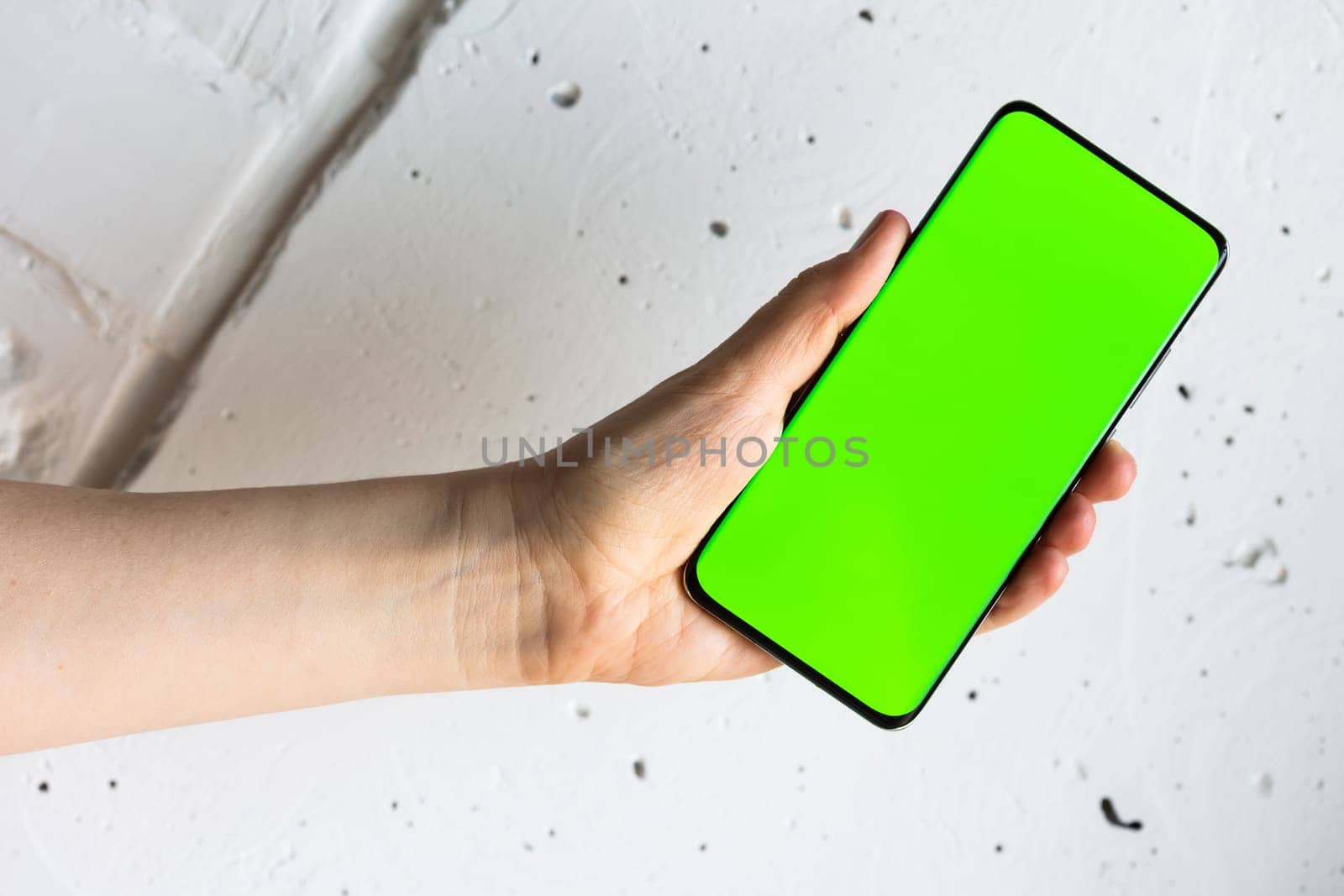 Mockup image of a person holding smart mobile phone with blank green screen