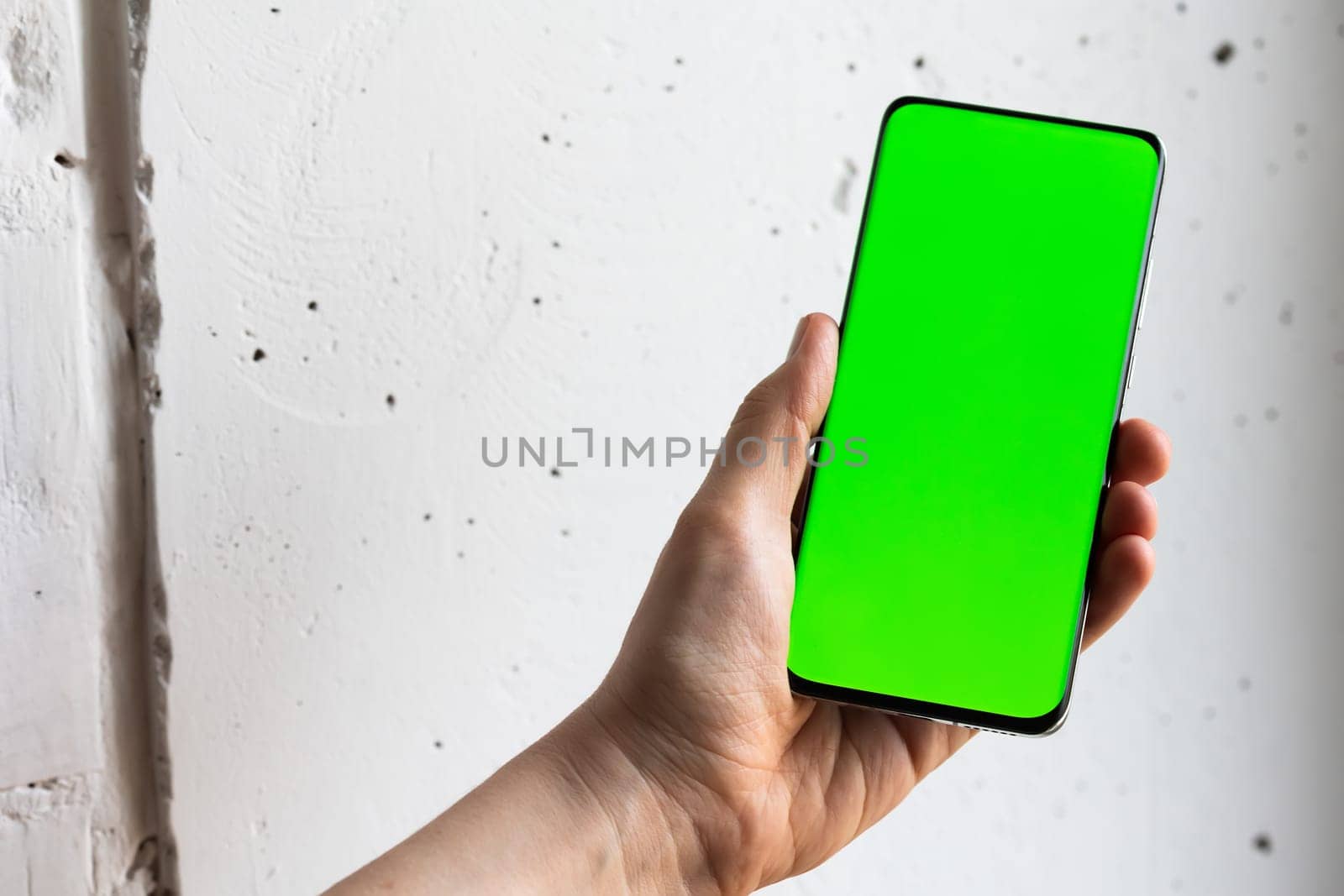 Mockup image of a person holding smart mobile phone with blank green screen