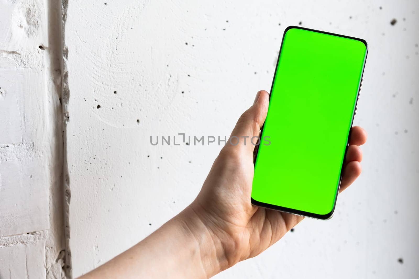 Mockup image of a person holding smart mobile phone with blank green screen