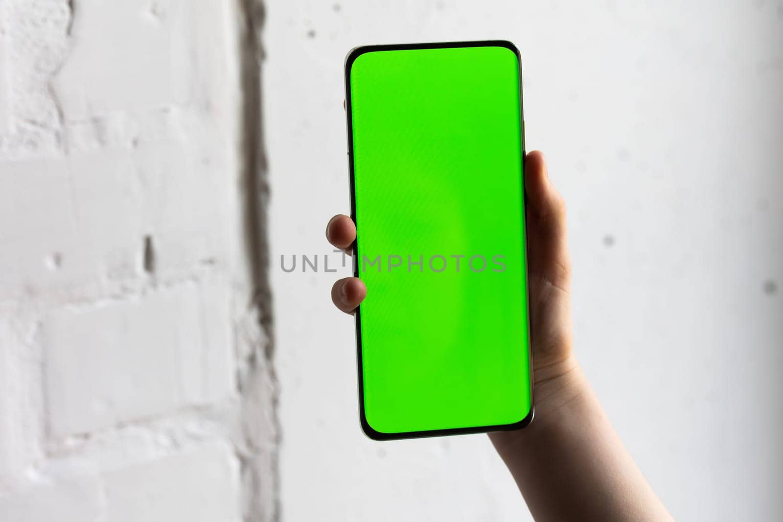 Mockup image of a person holding smart mobile phone with blank green screen