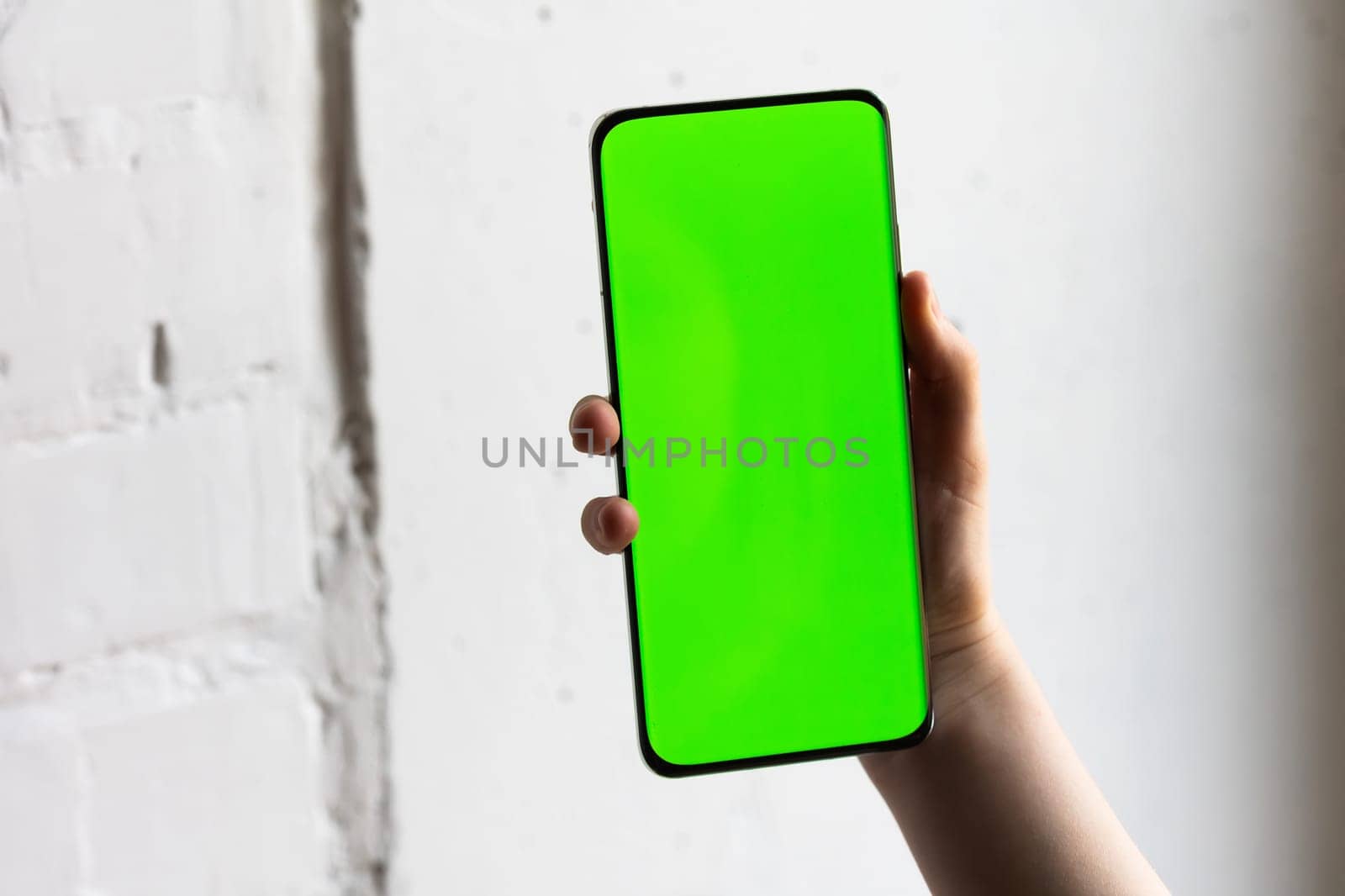 Mockup image of a person holding smart mobile phone with blank green screen. by sarymsakov