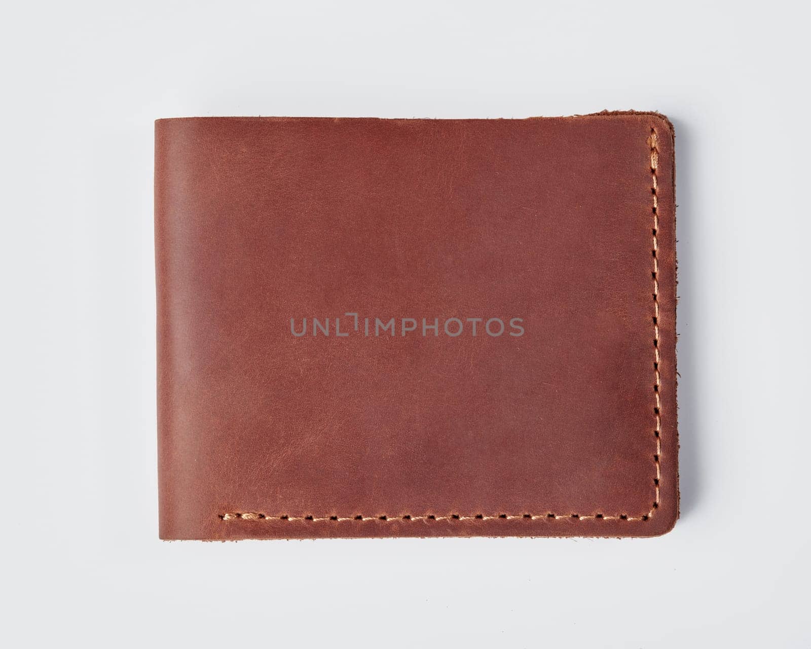 Closeup of stylish slim mens custom billfold wallet made of genuine copper colored leather with decorative stitching and William name embossed on light background