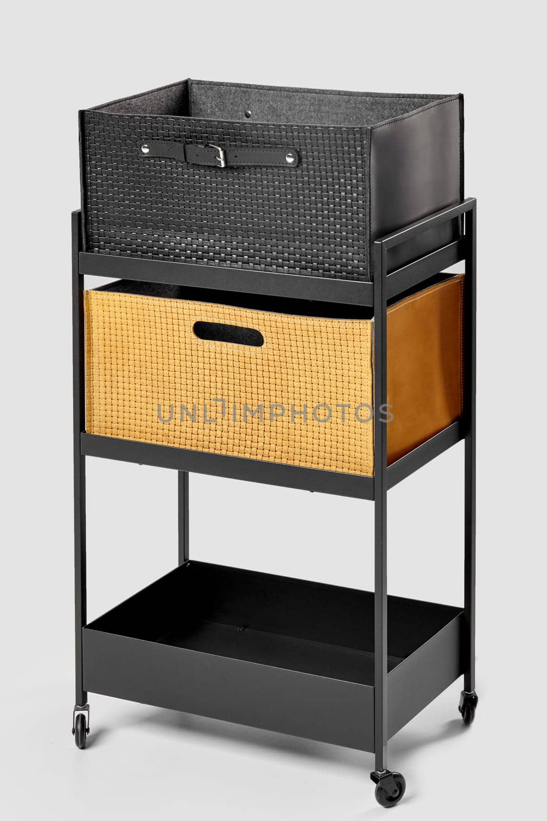 Two functional artisanal woven storage containers, in black leather and yellow suede decorated with slotted and applied strap handles thoughtfully positioned on practical metal office cart