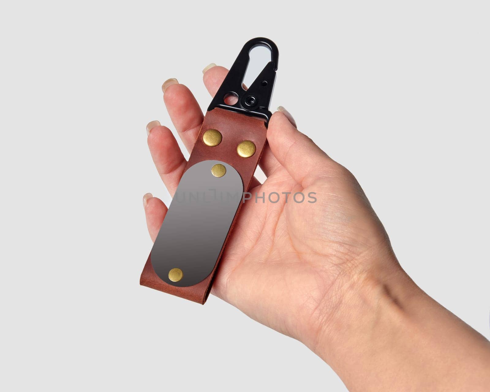 Female hand displaying bespoke brown leather keychain with durable metal carabiner clasp and cute baby photo, isolated on white. Ideal personalized handcrafted gift