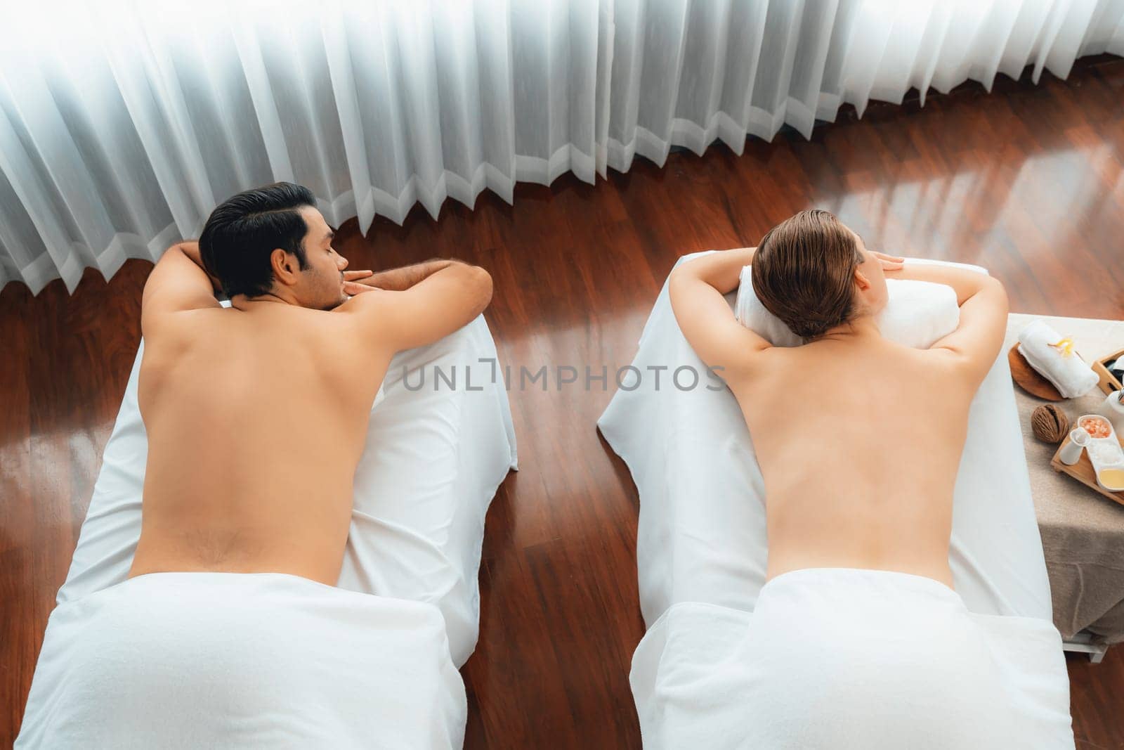 Top view caucasian couple customer enjoying relaxing anti-stress spa massage and pampering with beauty skin recreation leisure in day light ambient salon spa at luxury resort or hotel. Quiescent