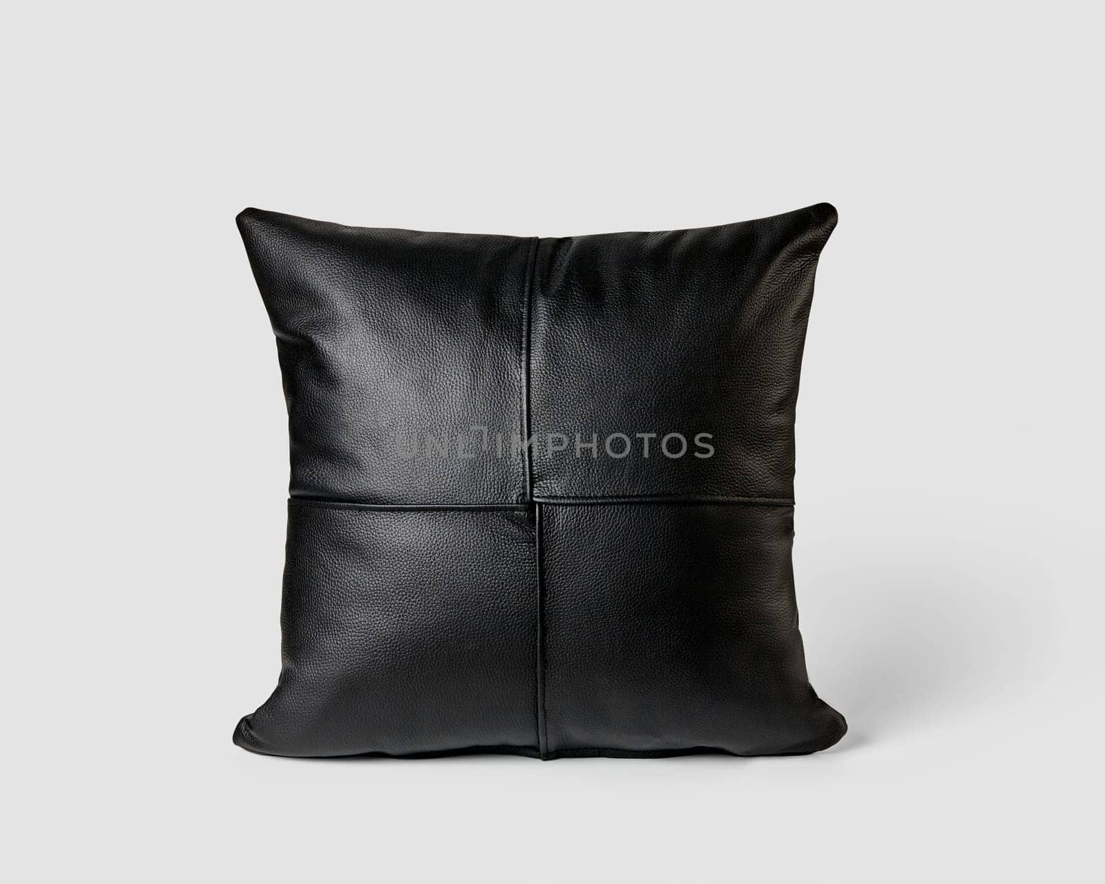 Elegant couch cushion featuring made of neatly stitched patches of smooth black leather isolated on white background. Handcrafted interior design item