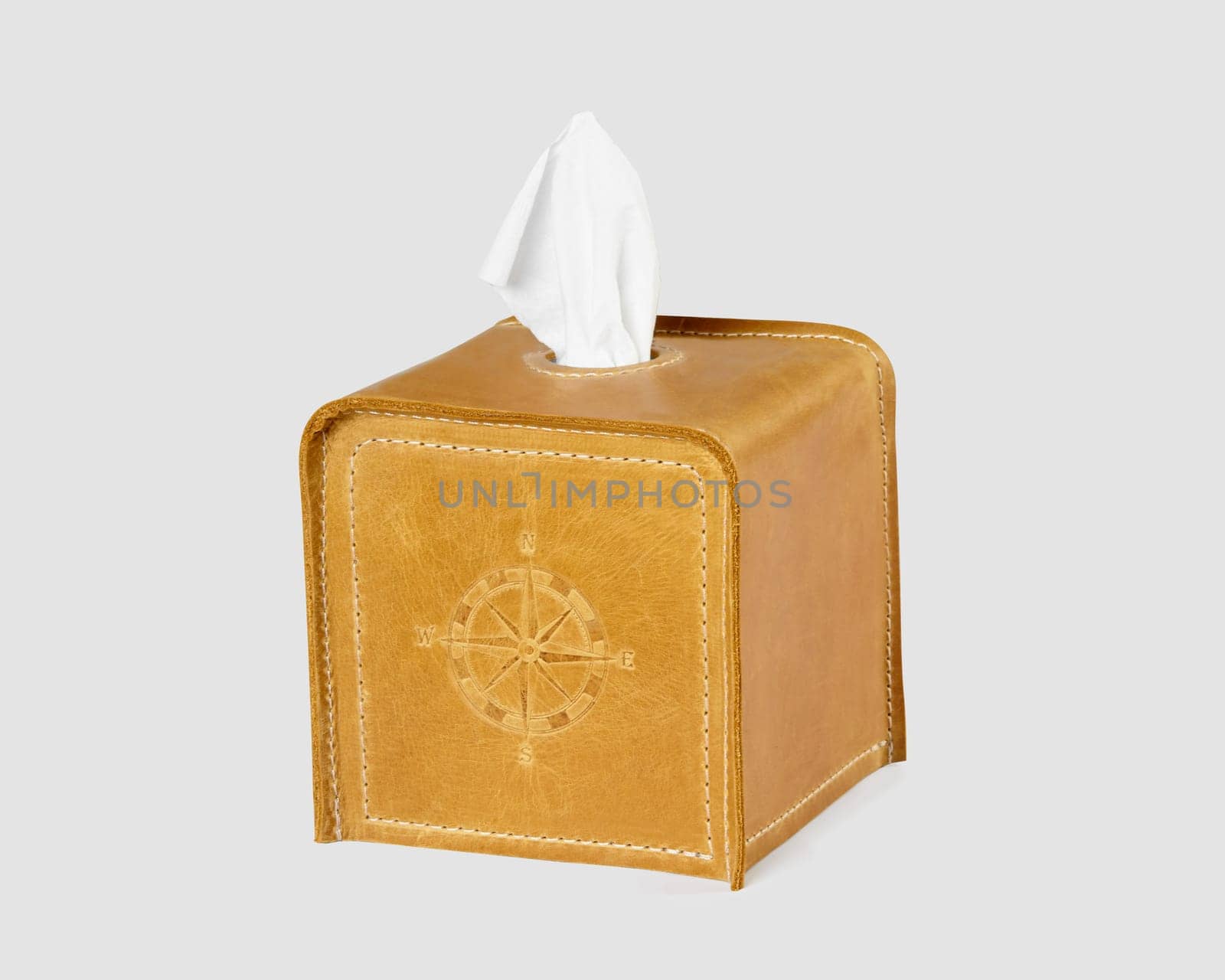 Stylish tan leather tissue box cover featuring compass embossing, isolated against white background. Stylish handcrafted home decor accessory