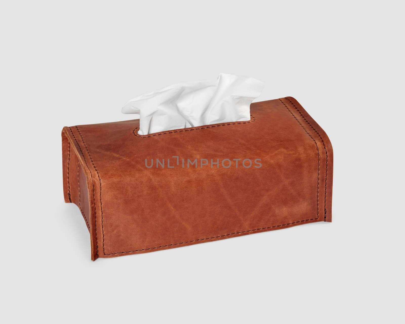 Stylish minimalist brown leather tissue box cover decorated with embossed letters, isolated on white background. Craft accessory for interior decor