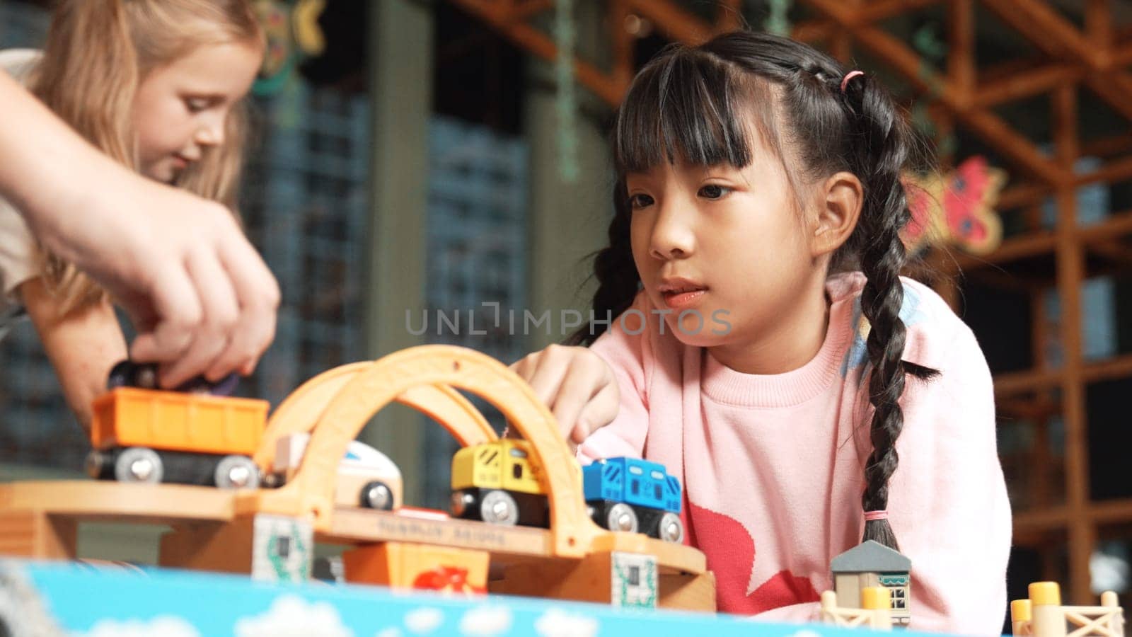 Closeup of cute asian girl play car toy with friend at play room. Diverse children using car model to improve imagination. Adorable children enjoy playing robotic model. Educational game. Erudition.