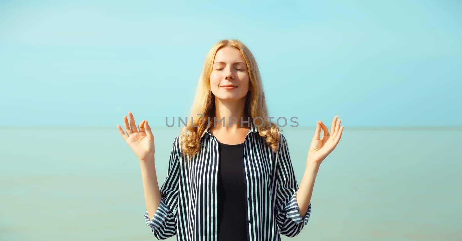 Calm relaxing healthy young woman meditates, practicing yoga on sea by Rohappy