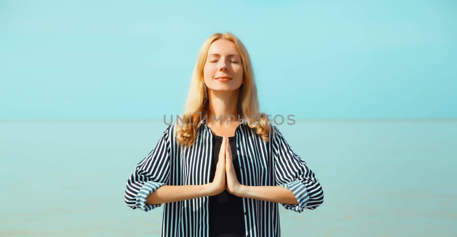 Calm relaxing healthy young woman meditates, practicing yoga on sea by Rohappy