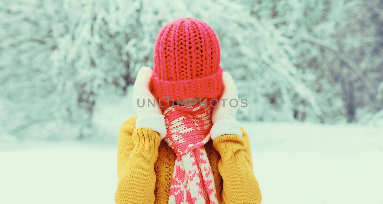Winter portrait of happy cheerful smiling young woman having fun in colorful knitted hat, scarf enjoys weather in snowy park