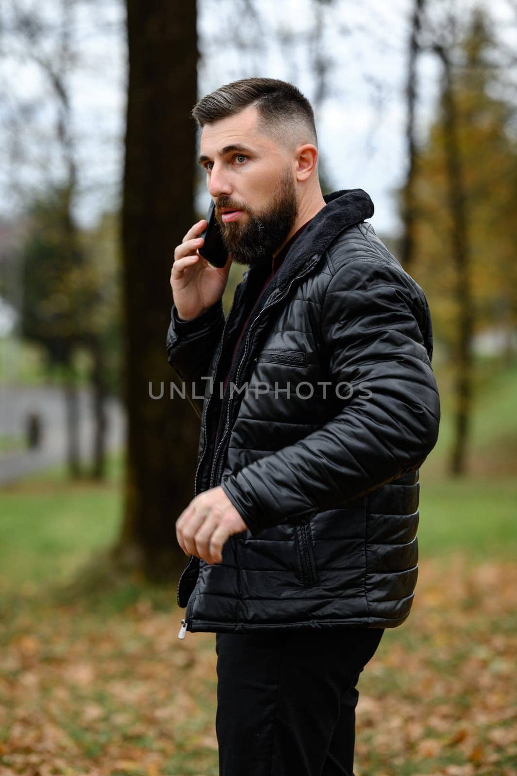 A man of elegant appearance is talking on the phone in the park, portrait of a man with a phone.