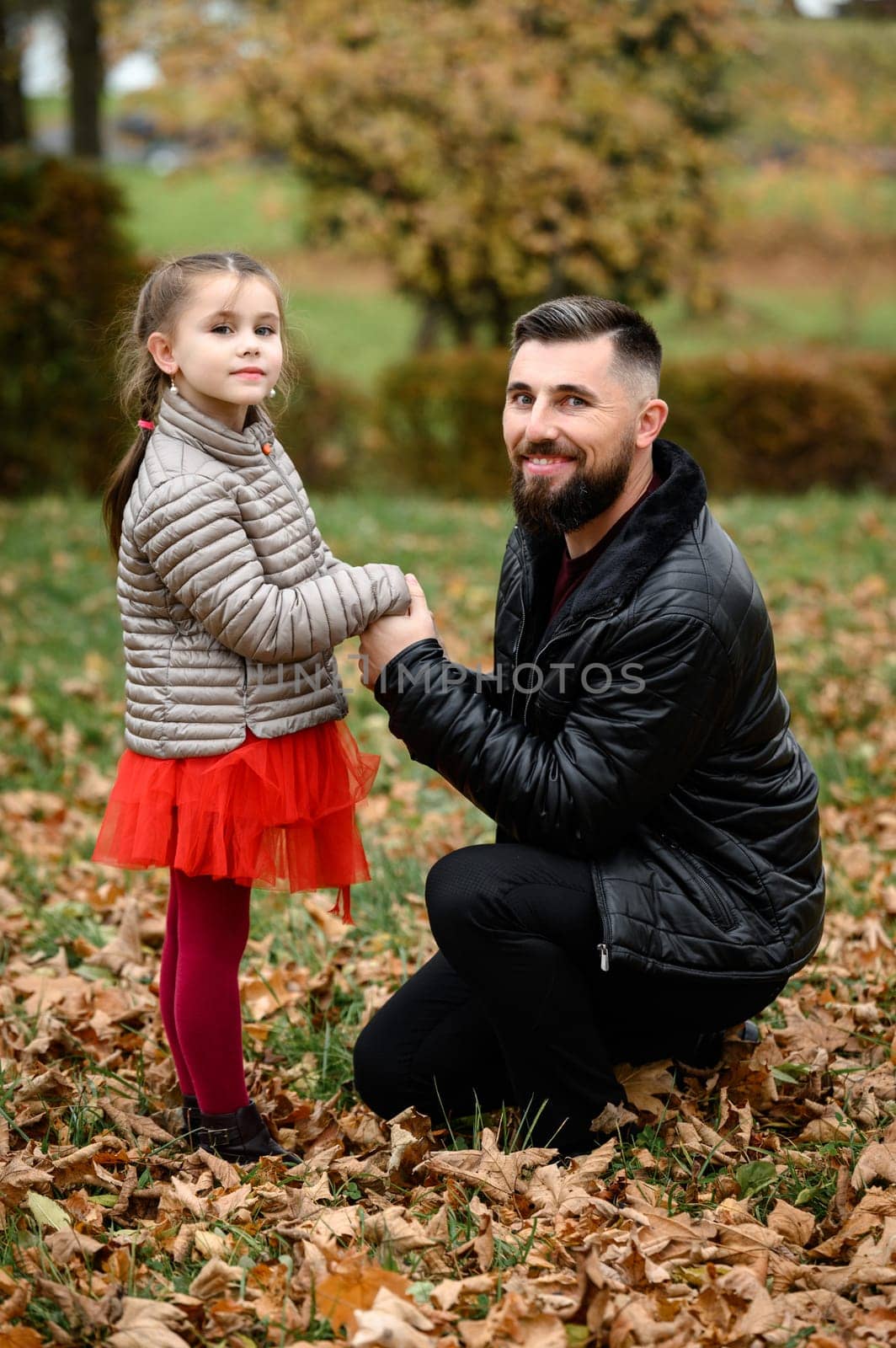Portrait of dad with daughter in autumn park with yellow leaves, parenthood.