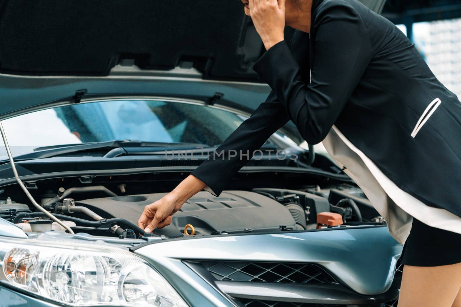 Young businesswoman whose car breakdown uses mobile phone to call for roadside assistance service. Travel and transportation vehicle problem. uds