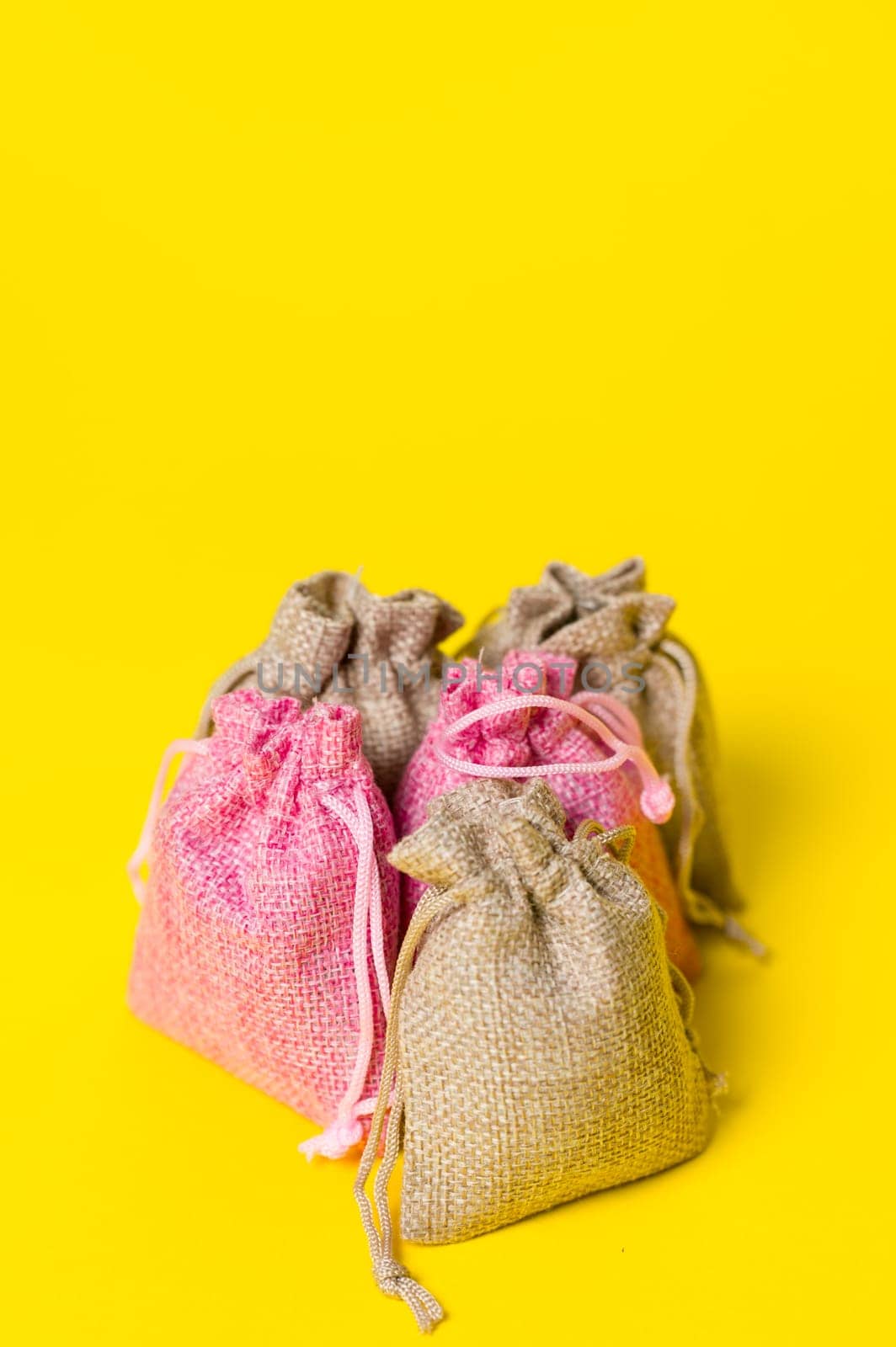 Lavender flower in a linen bag on a yellow background, fragrant lavender sachet.