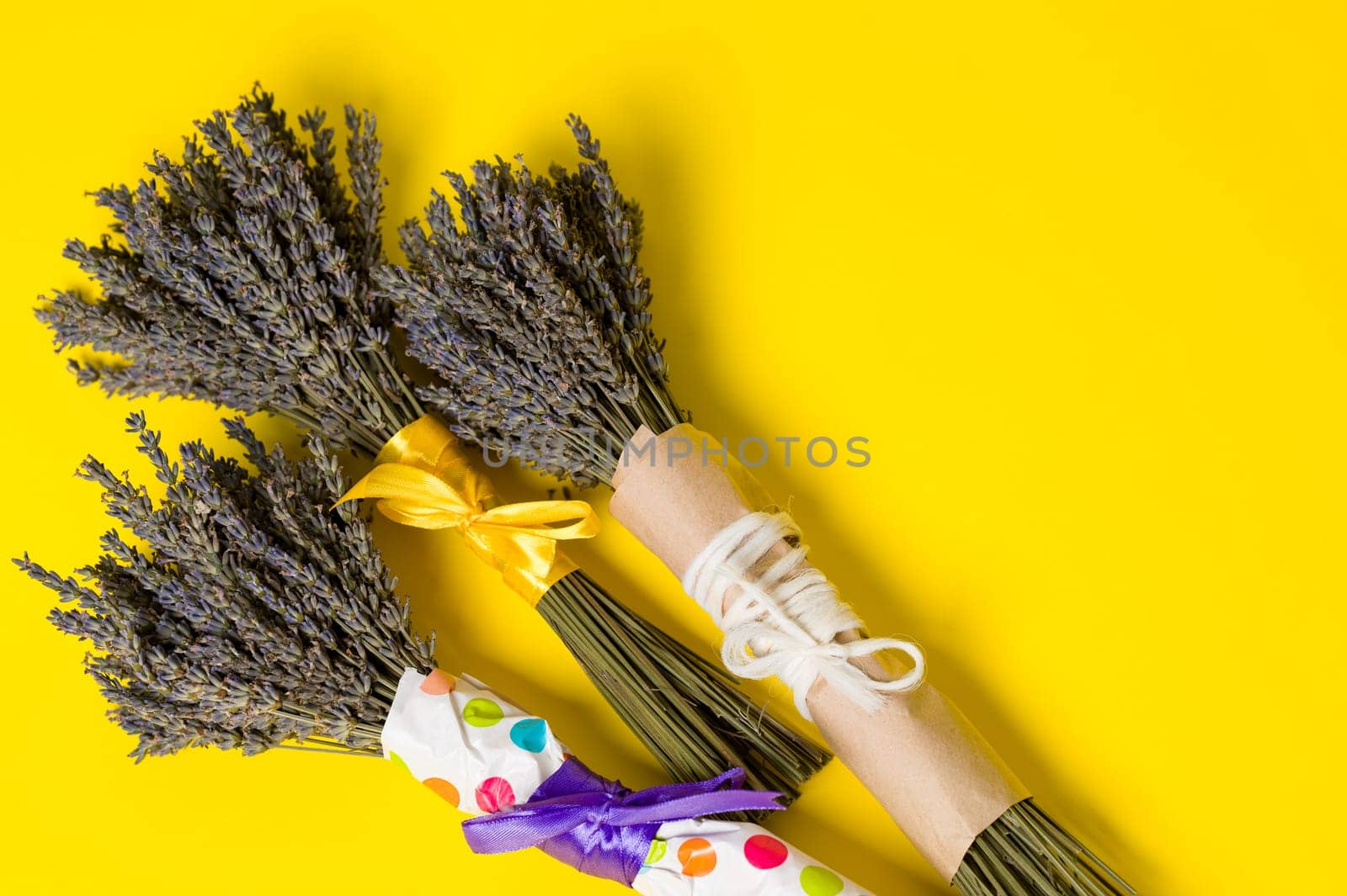 Three bouquets of dried lavender on a yellow background, lavender is a cosmetic plant.