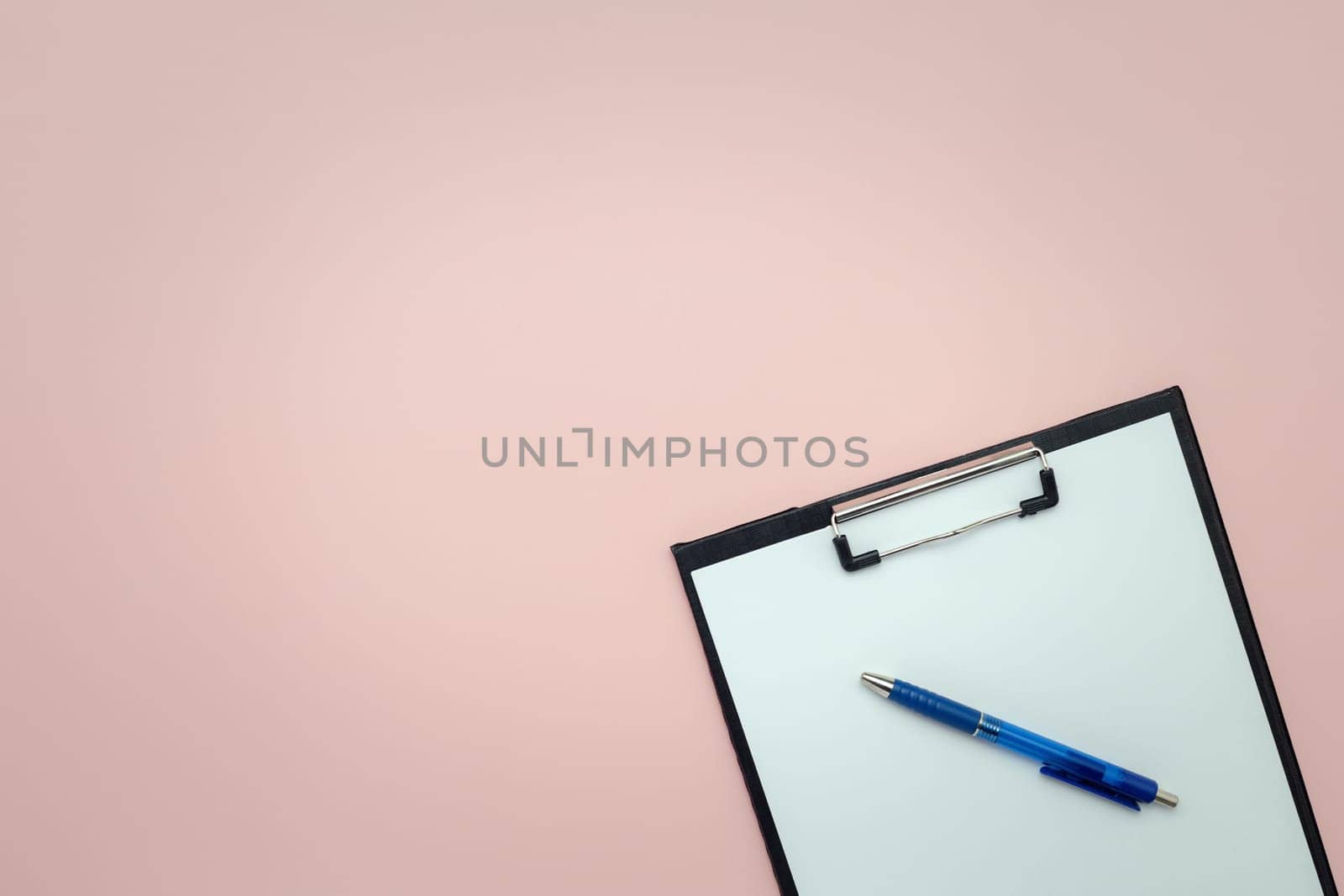 Clipboard and pen with empty pages for writing and sketching on pink background by iamnoonmai