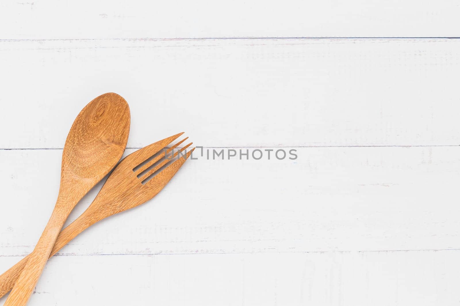 Wooden kitchen utensils including a spoon and fork on white table background by iamnoonmai