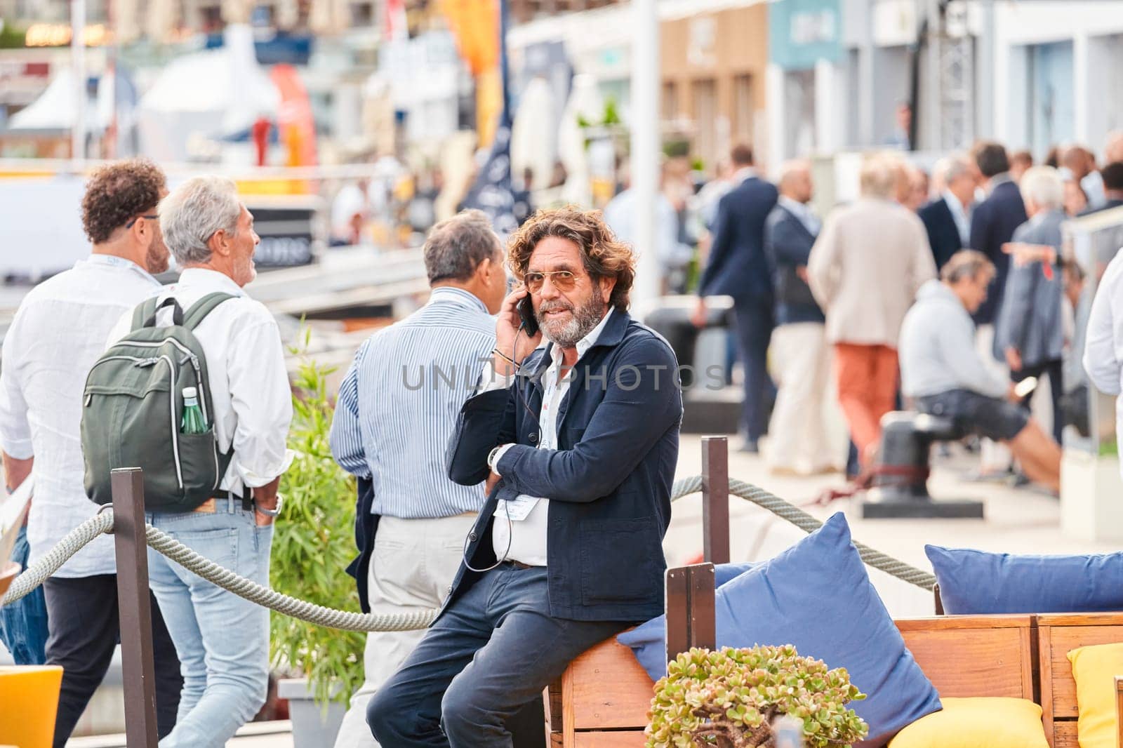 Monaco, Monte Carlo, 29 September 2022 - A stylish older man is sitting and talking on the phone at the famous motorboat exhibition, mega yacht show, clients and yacht brokers discuss the novelties. High quality photo