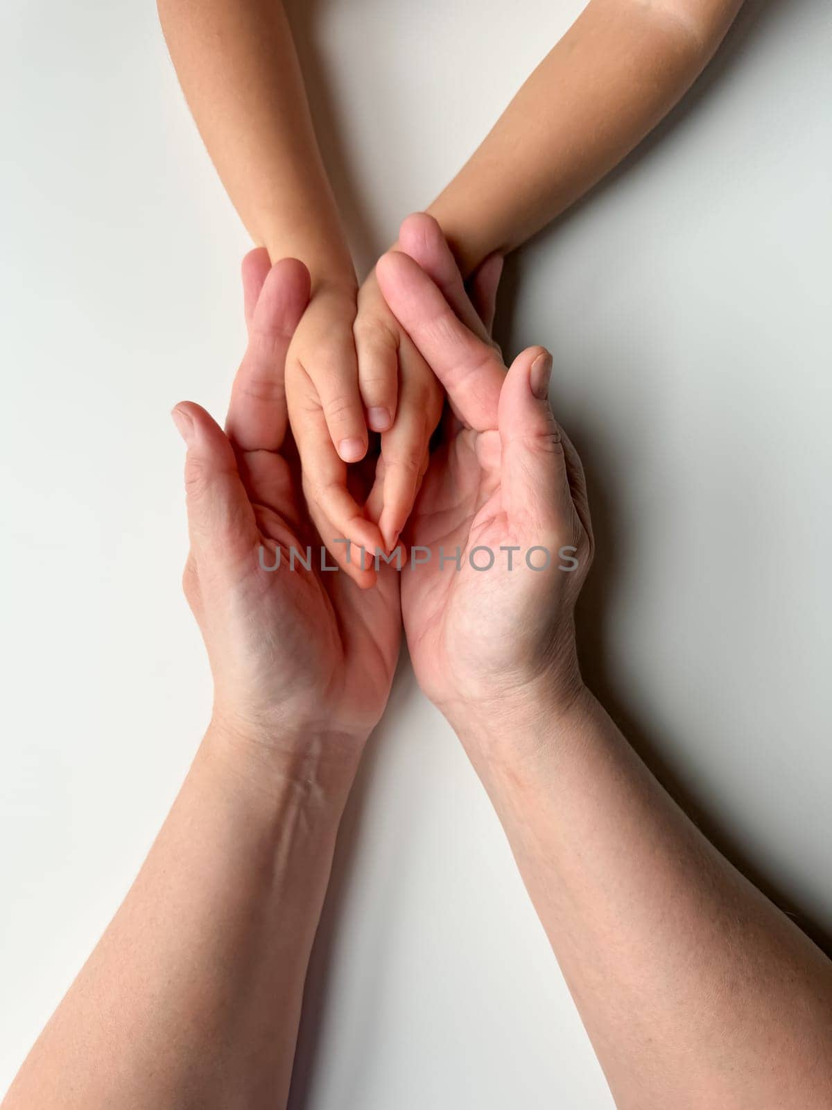 Mothers hands holding childs hands on a white background. by Lunnica