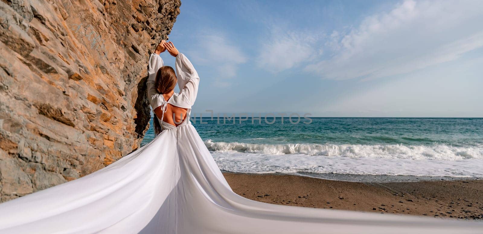 Woman beach white dress flying on Wind. Summer Vacation. A happy woman takes vacation photos to send to friends