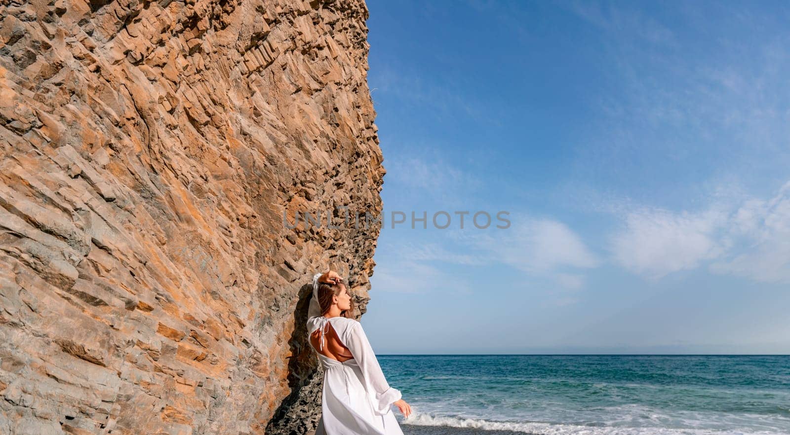 Woman beach white dress flying on Wind. Summer Vacation. A happy woman takes vacation photos to send to friends