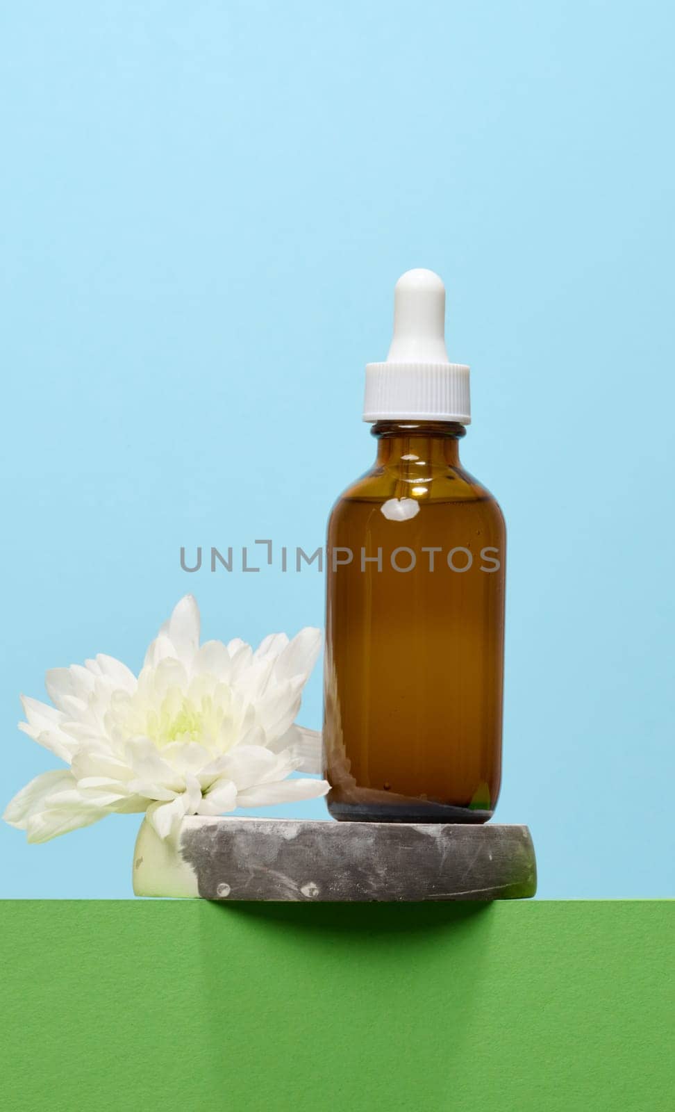 A glass brown bottle with a dropper on a blue background, a container for cosmetic products.  by ndanko
