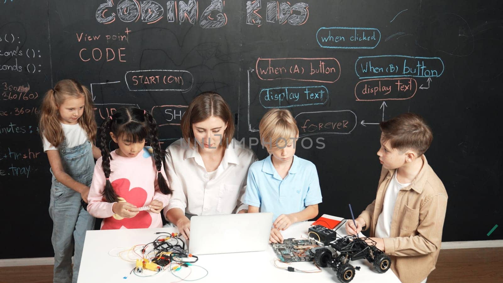 Diverse student writing engineering code while boy fixing mother board. Teacher giving advice and teaching about robotic system while learner studying and learning about coding prompt. Erudition.