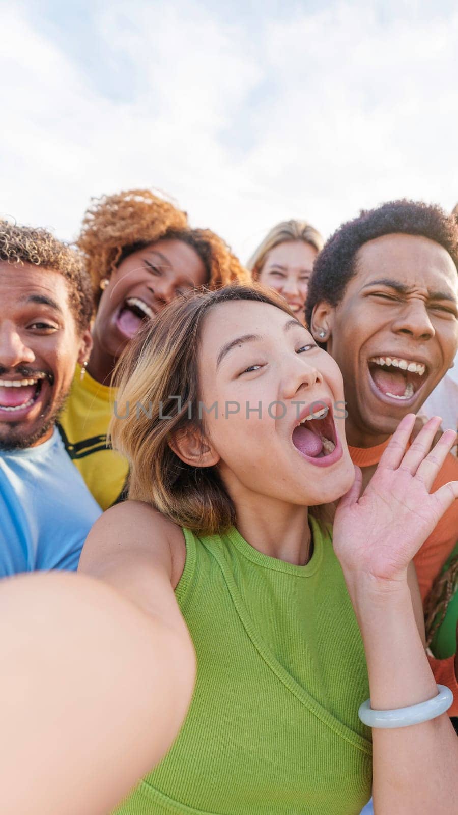 Chinese woman taking selfie with multiethnic friends outdoors. Vertical shoot