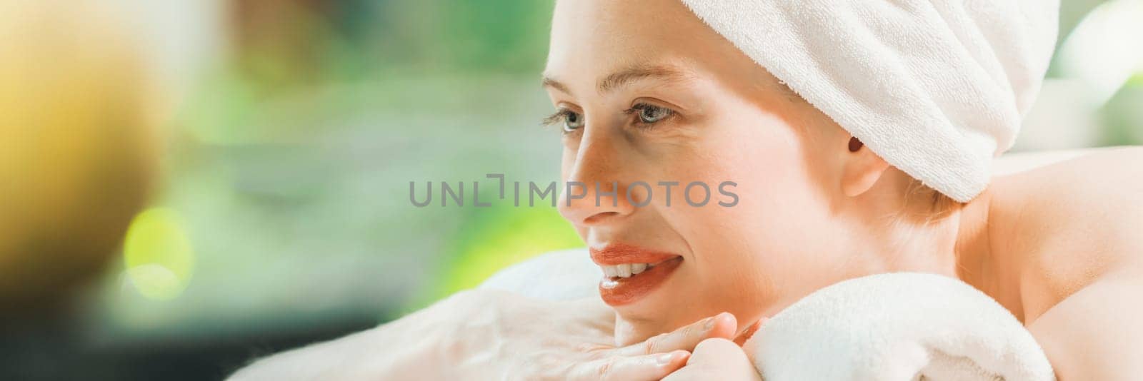 Closeup of beautiful women in white towel relaxes on spa bed surrounded by peaceful and calm nature. Young gorgeous female wearing white towel during waiting for body massage. Side view. Tranquility