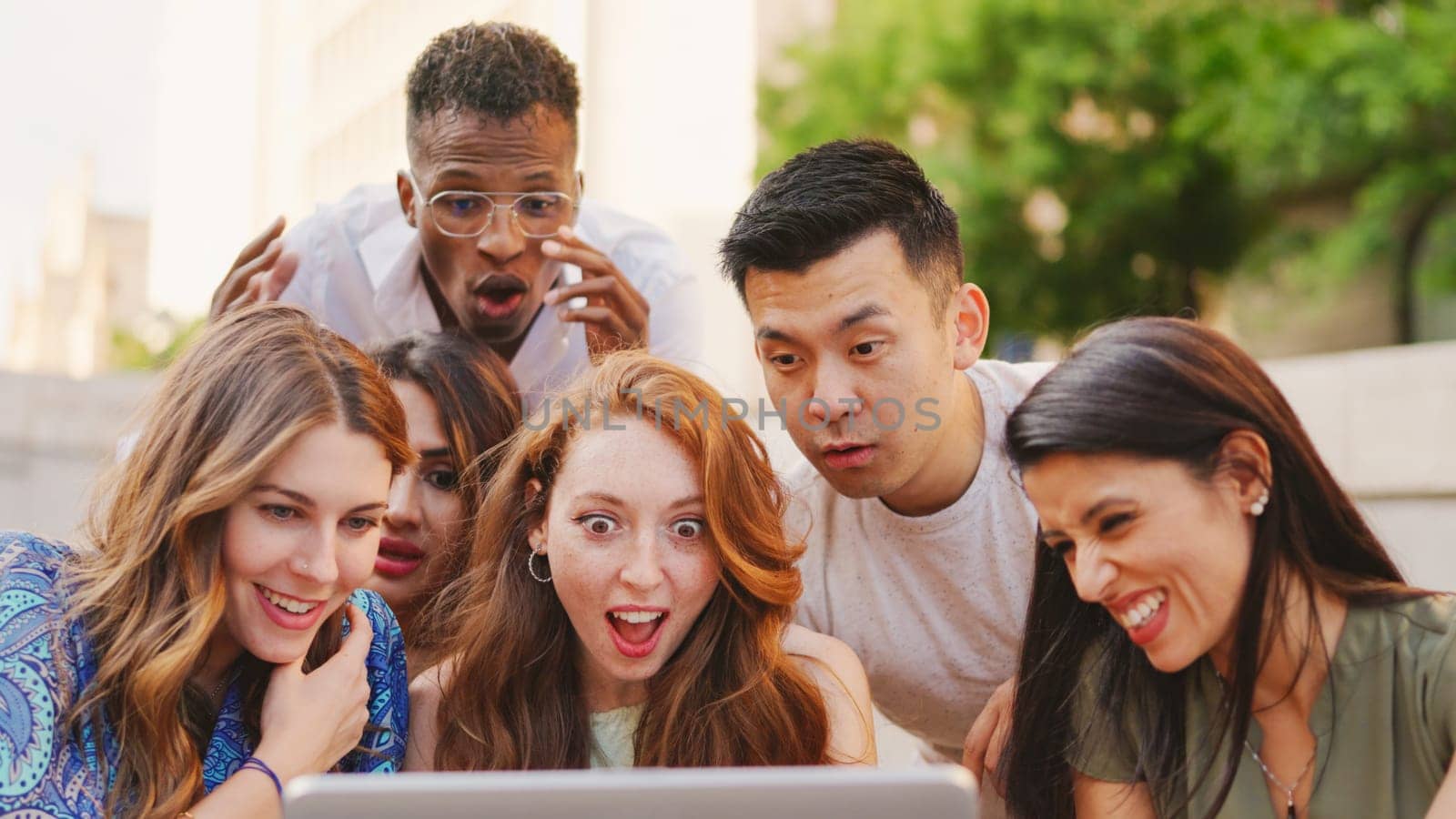 Multiethnic group of people looking at a laptop with surprised expression by ivanmoreno