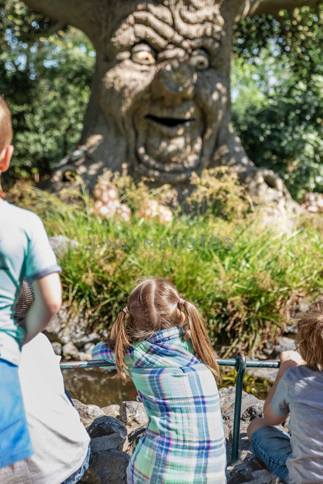 KAATSHEUVEL, NETHERLANDS - APRIL 19, 2019: An old tree tells children legends and fairy tales in a Park EftelingSelective focus on a girl