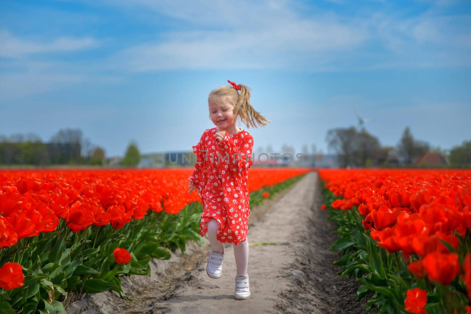 Happy girl running in a red tulip field