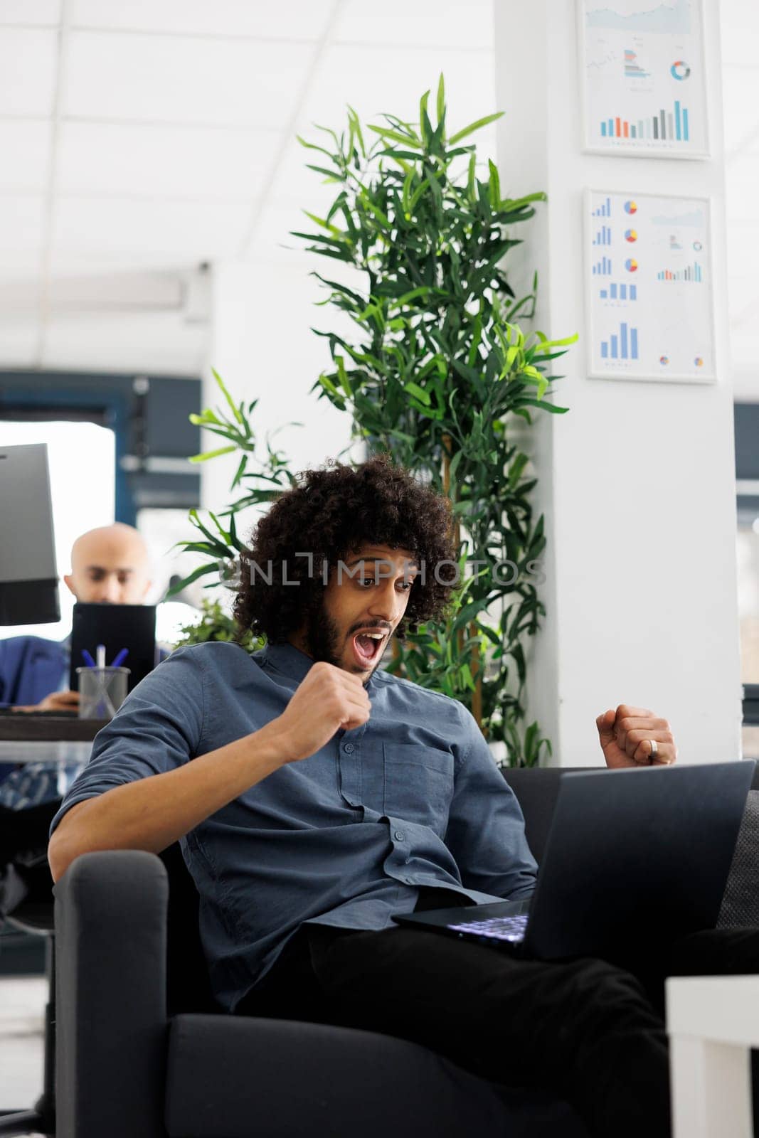 Businessman celebrating sales growth while analyzing report on laptop by DCStudio