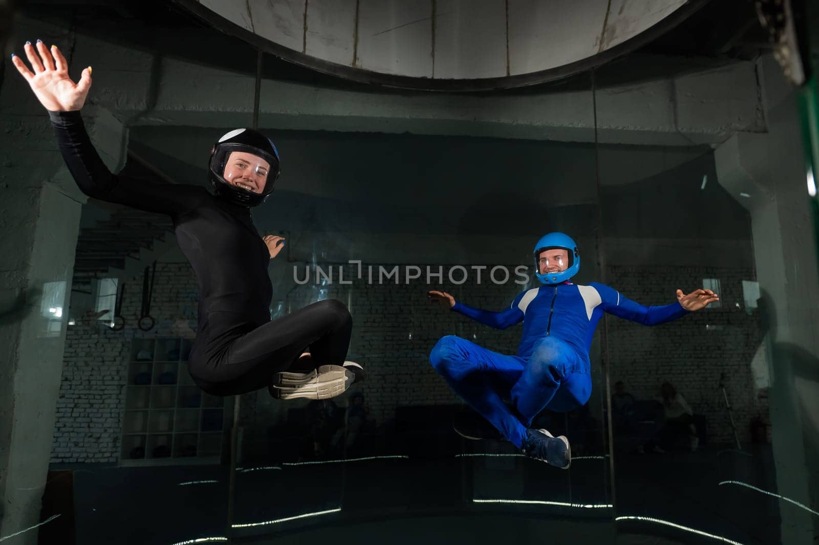 A man and a woman enjoy flying together in a wind tunnel. Free fall simulator.